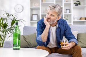 a man sitting on a couch while holding a glass of alcohol